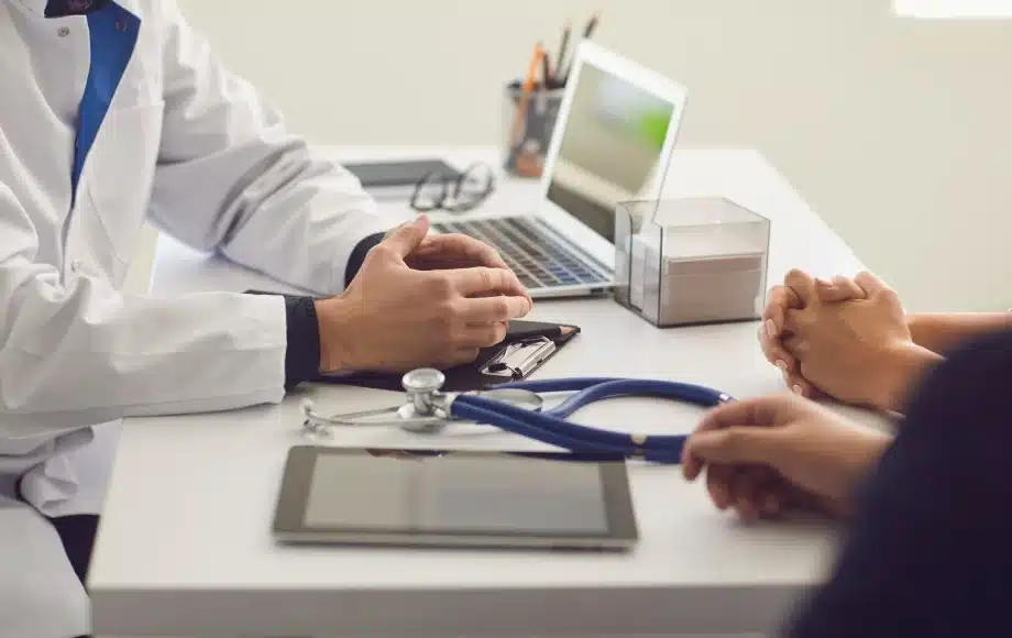 Doctor and 2 people's hands pictured at a desk. It appears they are discussing something important before surgery