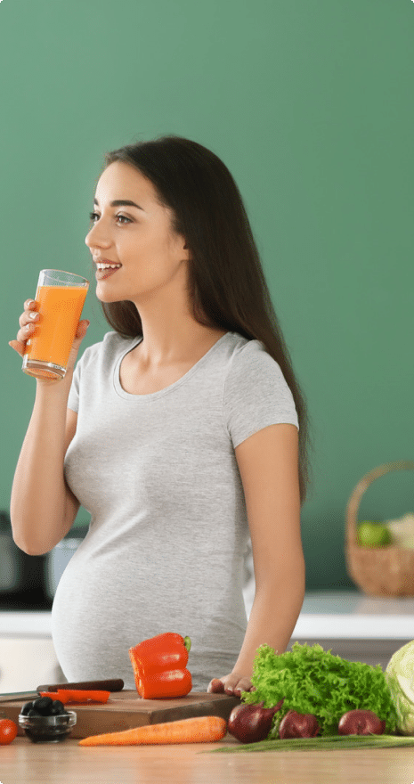 Woman holding a healthy drink to her lips that is pregnant