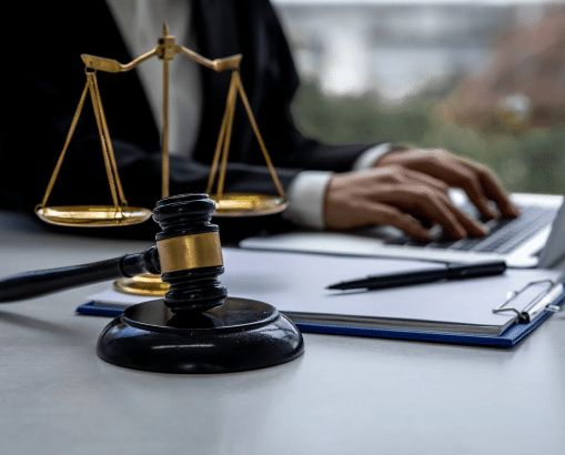 Medical malpractice attorney typing on the computer. The scales of justice are in camera view next to her on the desk